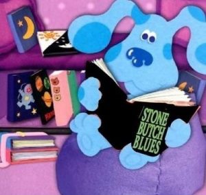 Scooby Doo on a purple beanbag reading Stone Butch Blues by Leslie Feinberg