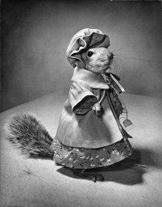 A squirrel wearing a coat and bonnet