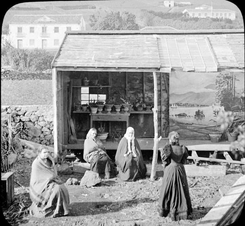 Black-and-white photograph of four women gathered around shed(?) on Faial Island, Azores.