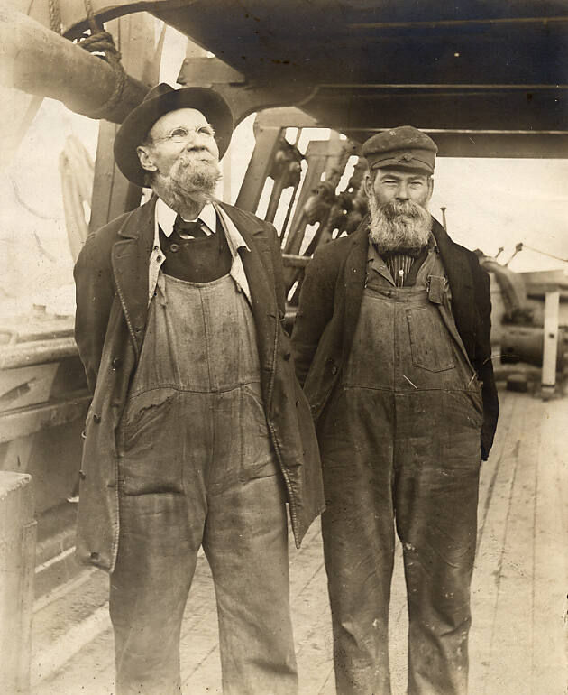 Black-and-white photograph of two middle-aged men in overalls on deck of whaling ship.