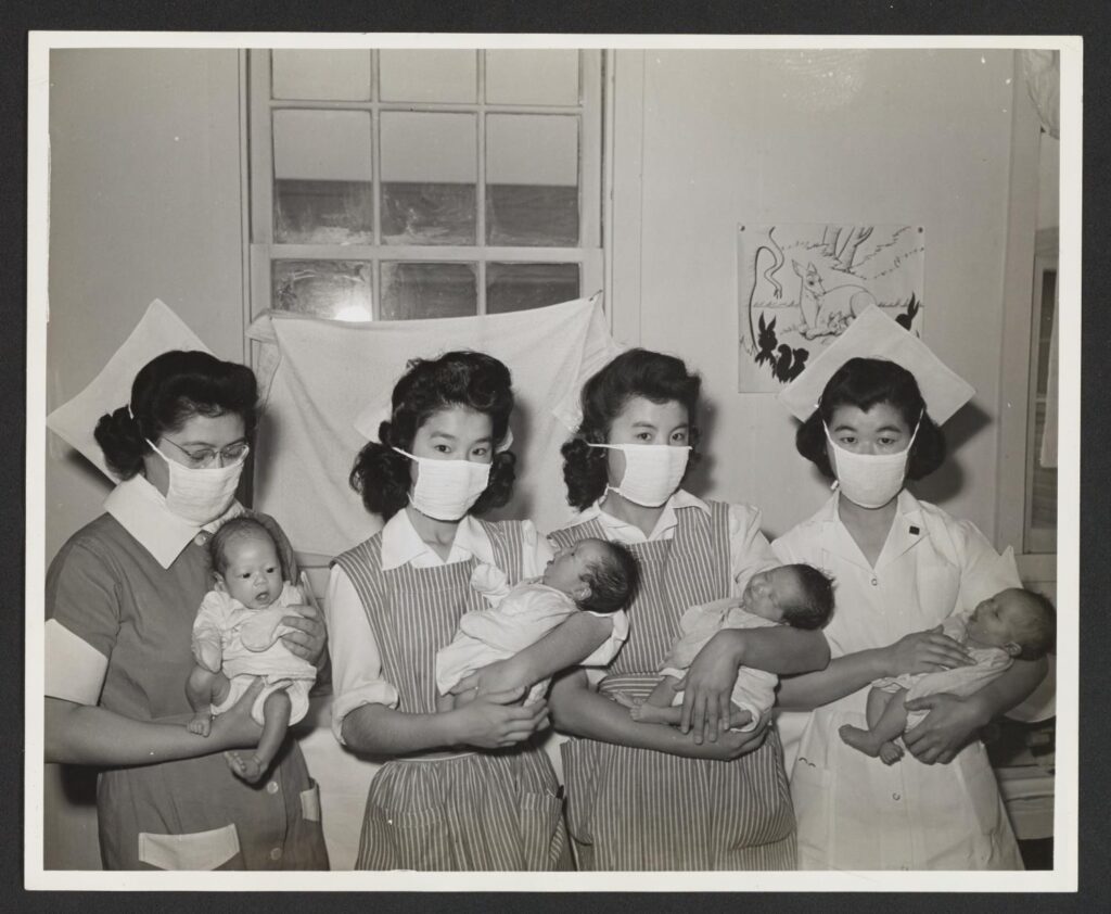 Black and white photograph of four nurses holding babies at Tule Lake Relocation Center