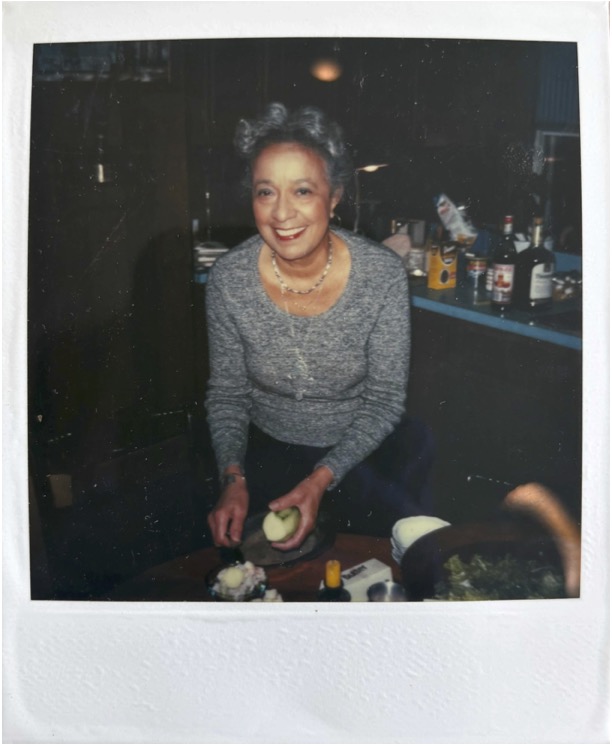 Color polaroid of Adelaide Cromwell smiling and cutting cucumber. Date: unknown