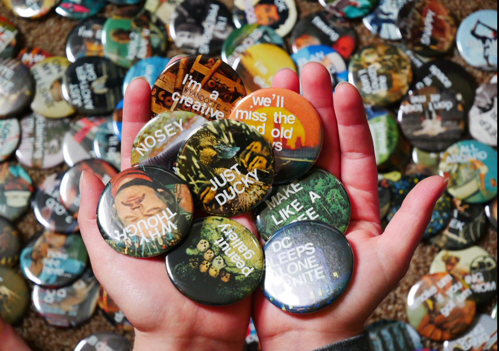 Pile of buttons. Visible sayings include "Just Ducky", "Nosey ..." "We'll miss the ... old ..."