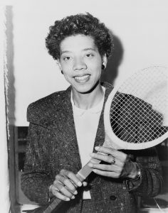 black and white photograph of Gibson holding a tennis racquet