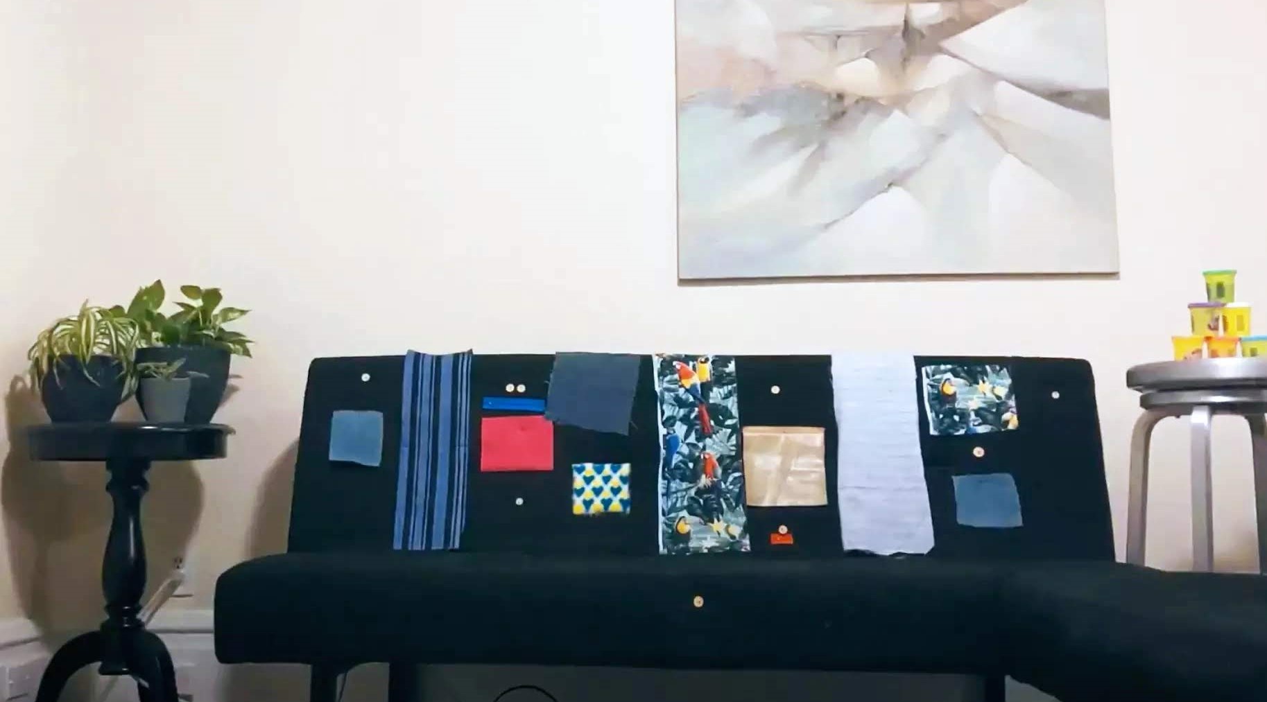 Image of a black living room couch, decorated with pinned scraps of cloth of different colors and patterns.