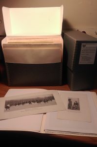 image of two archival boxes and an open folder displaying two photographs.