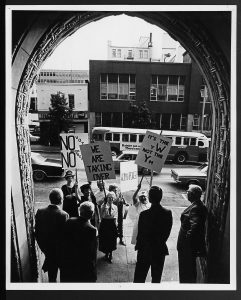 image of a group of women holding signs standing in front of a group of men