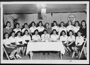 image of a group of girls seated and standing behind a table