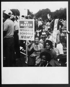 image of a group of demonstrators one holding a sign that says we march for integrated schools now