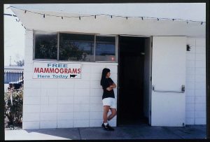 woman standing in front of a building and a sign that reads "free mammograms"