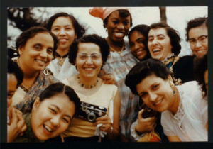 color photograph of a group of young women standing and leaning into one another all smiling