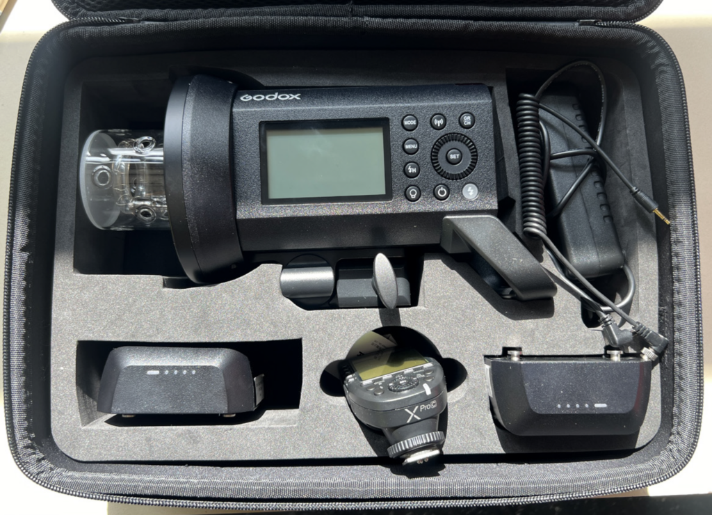 Figure 2: Clockwise from top - Monolight, charging cable, battery, wireless flash trigger, battery.