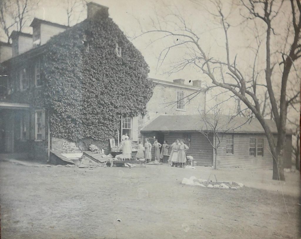 Image of a group of girls outside a house partially covered in ivy.