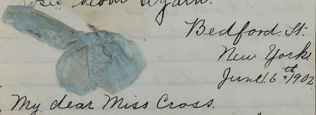 A small blue bow is stapled to the top of a letter.