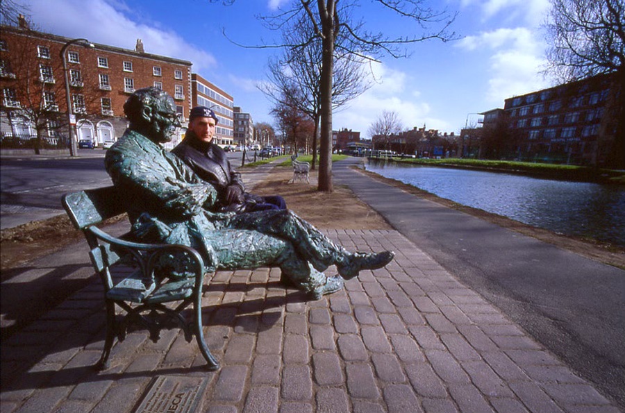 Denys sitting on a bench next to a statue