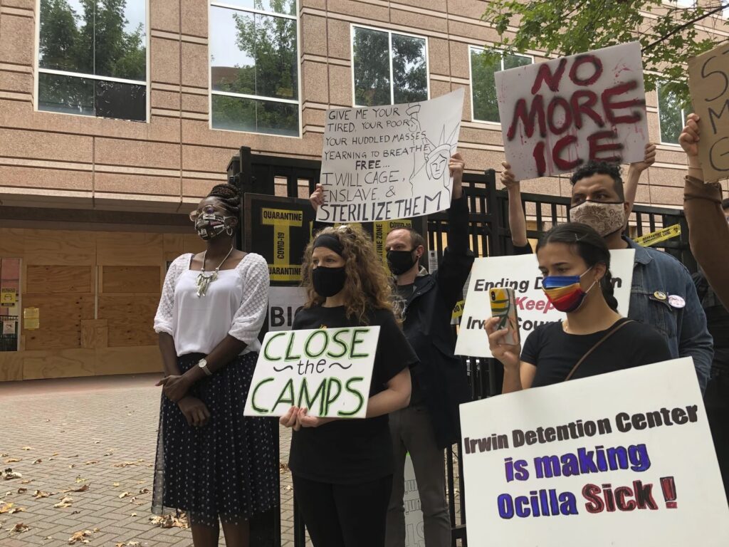protesters holding signs against ICE sterilization, with Dawn Wooten among them