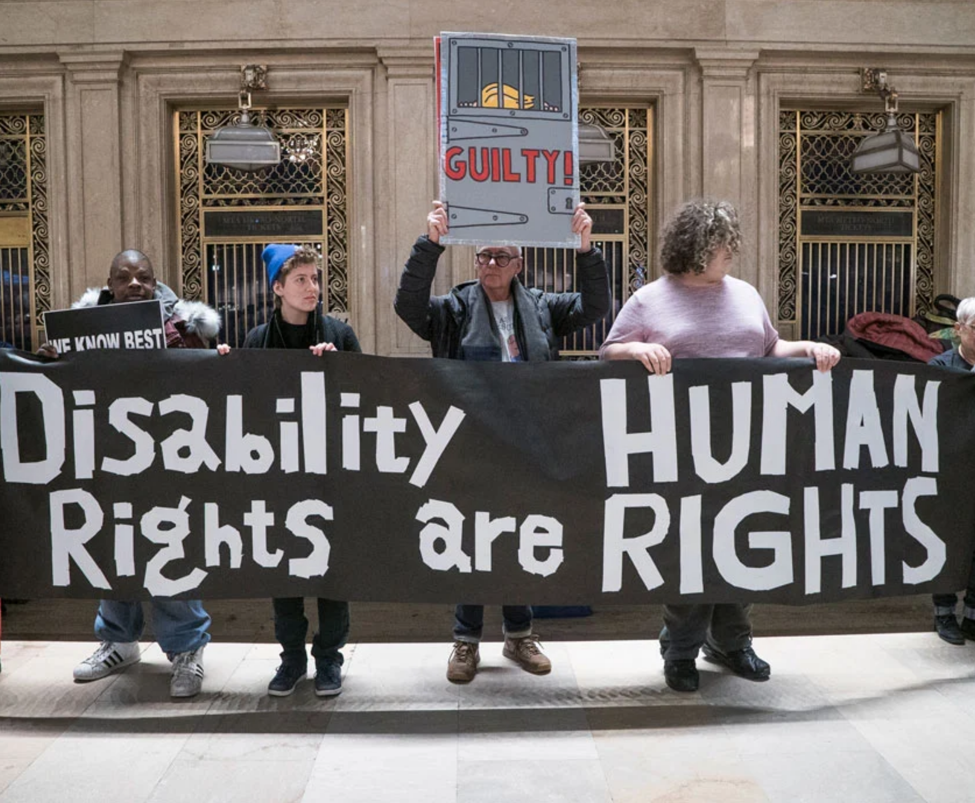 A group of people are out on the street collectively holding a giant sign saying "Disability Rights are Human Rights"