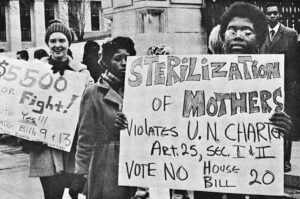 black and white photo of protesters holding a sign against sterilization