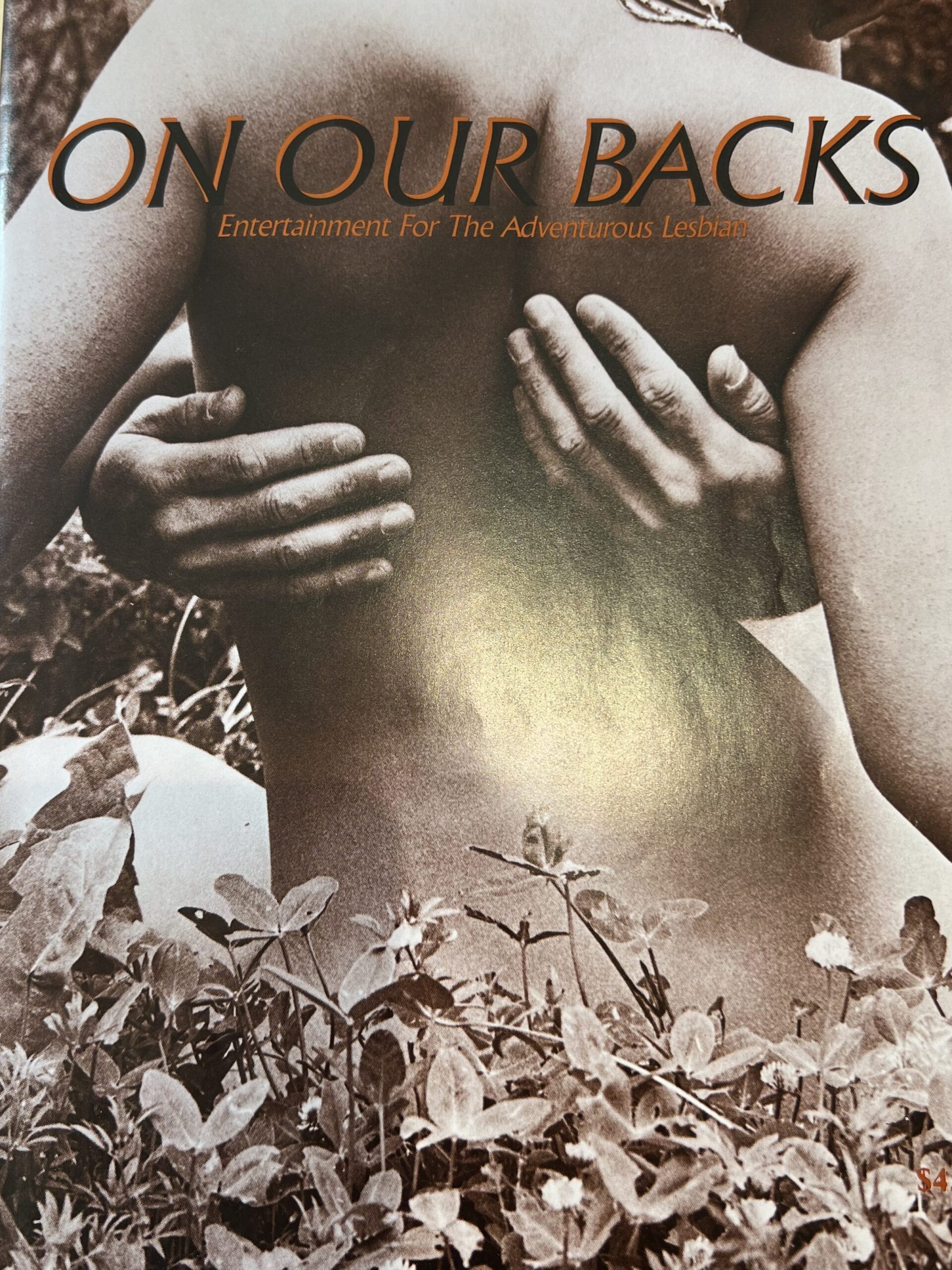 A magazine cover of a bare back with hands wrapped around it amidst leaves. Text reading: "ON OUR BACKS: Entertainment For The Adventurous Lesbian"