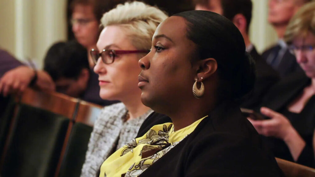 An image of Kelli Dillon, with an unnamed woman sitting behind her.