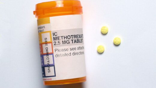 Orange pill bottle labeled Methotrexate 2.5 mg tablet next to three round, yellow pills