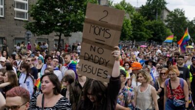 A woman at a gay rights protest holding a sign that says, "2 Moms- No Daddy Issues"