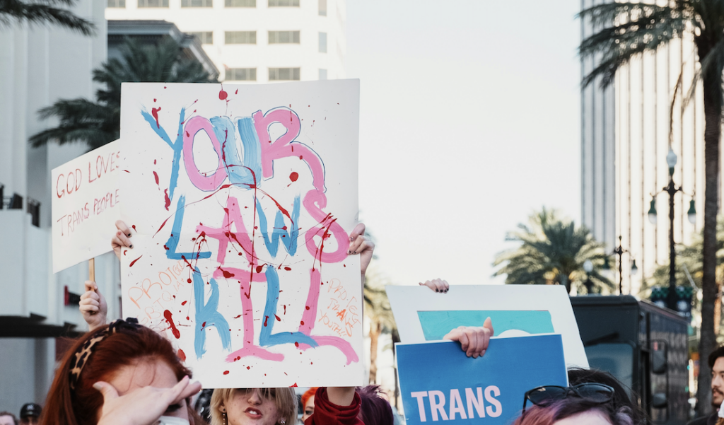 Your Laws Kill - Protest Sign in the trans* pride flags's colors and fake-blood-sprinkles