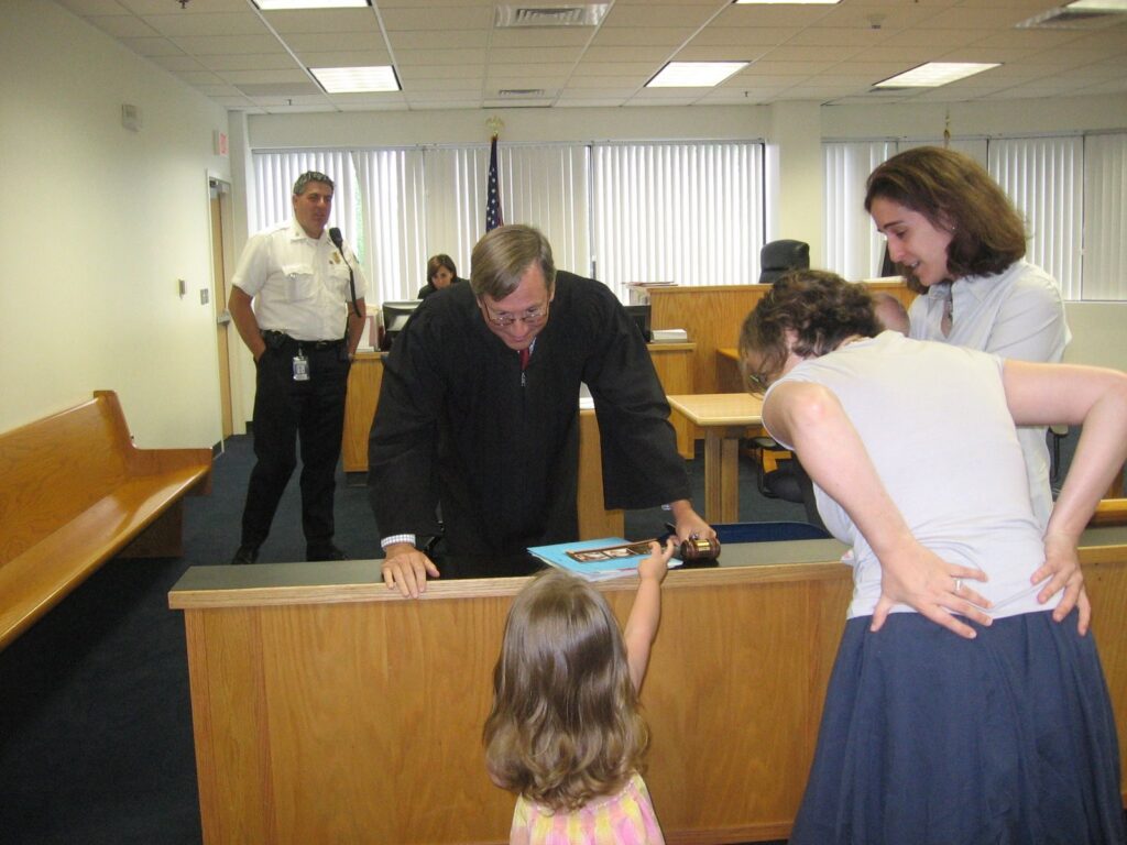 Judge talking to toddler aged Lucia holding a book