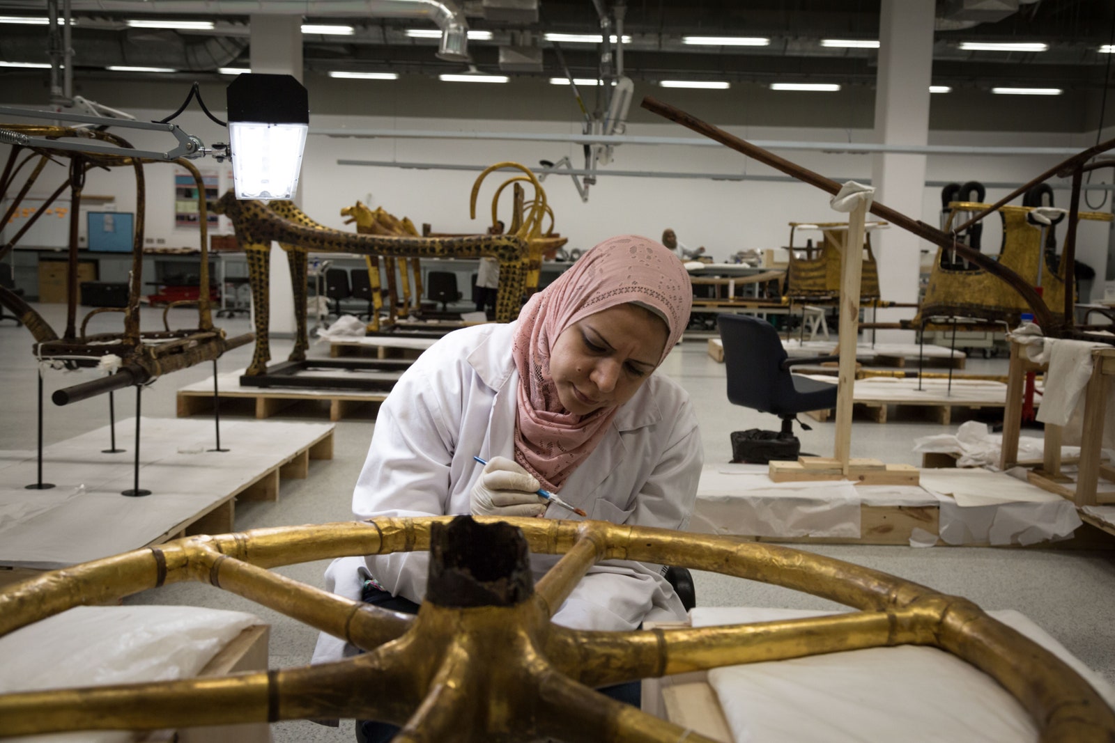 A conservator restores an ancient Egyptian artifact at the Grand Egyptian Museum in Cairo.