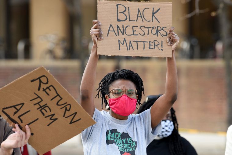 A protester at the Penn Museum holds a sign that reads "Black ancestors matter!"