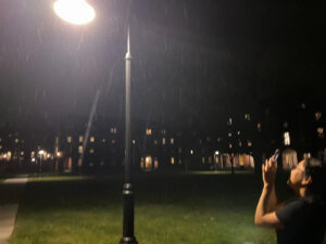 Student looking at the snow during the lamp light.