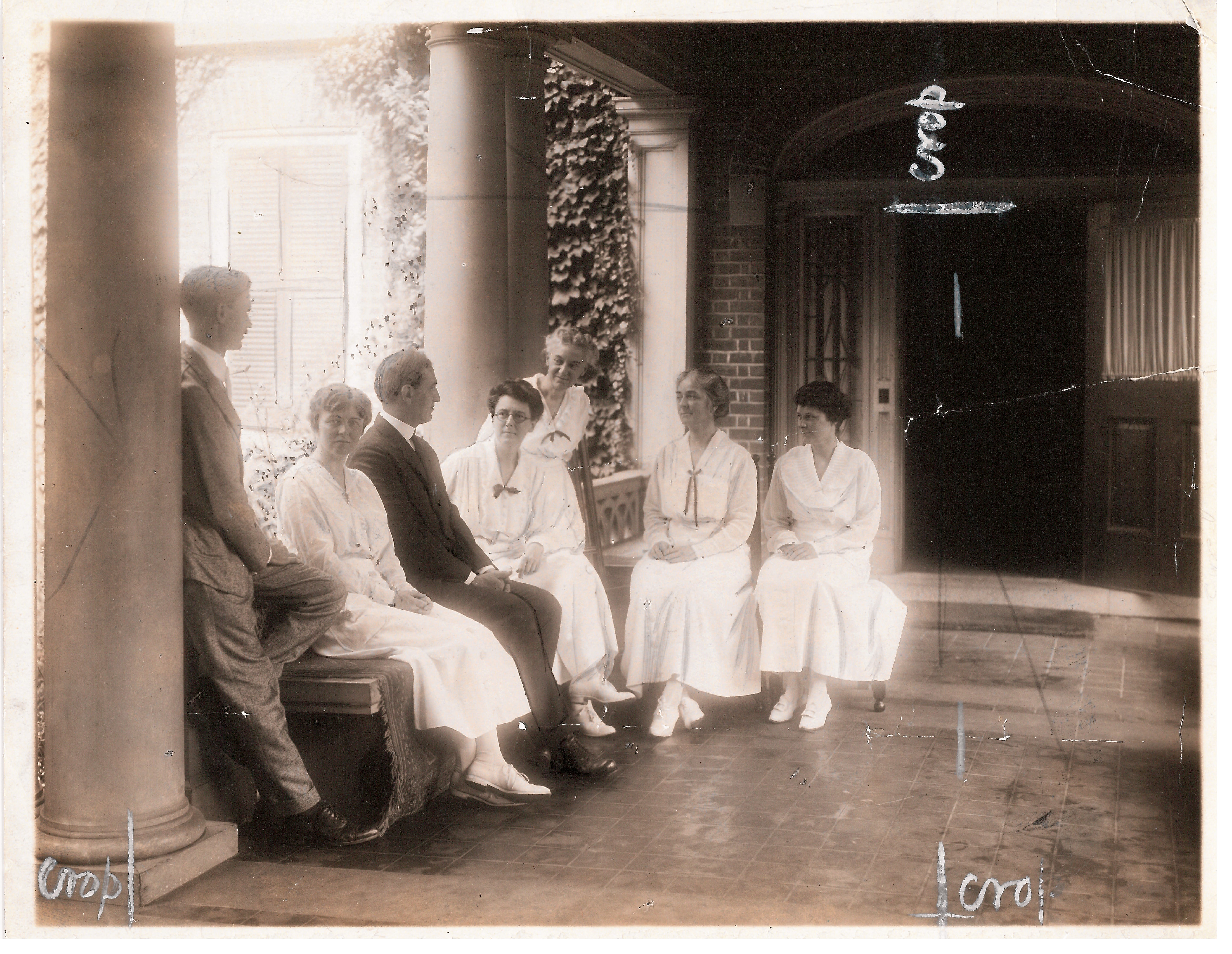 Black and white photo of faculty in formal dress on porch.