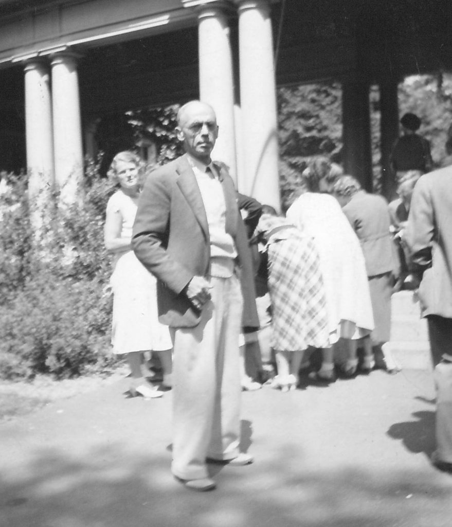 Black and white photo. Man in tweed jacket looking at camera