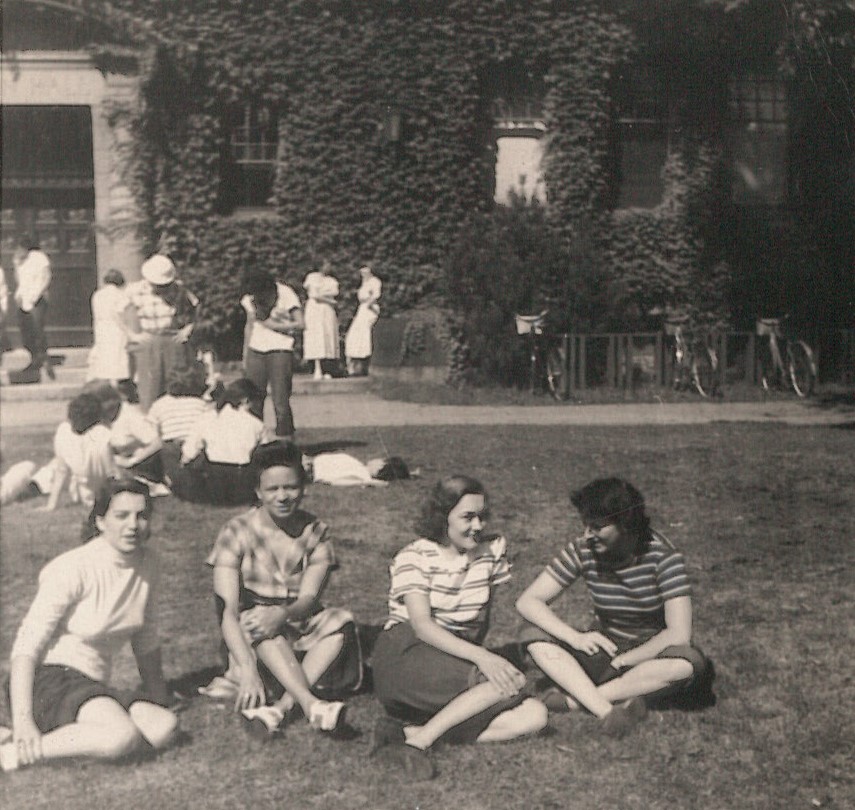 Black and white photo of several groups gathered on the lawn. In the foreground is an interracial group looking at the camera.