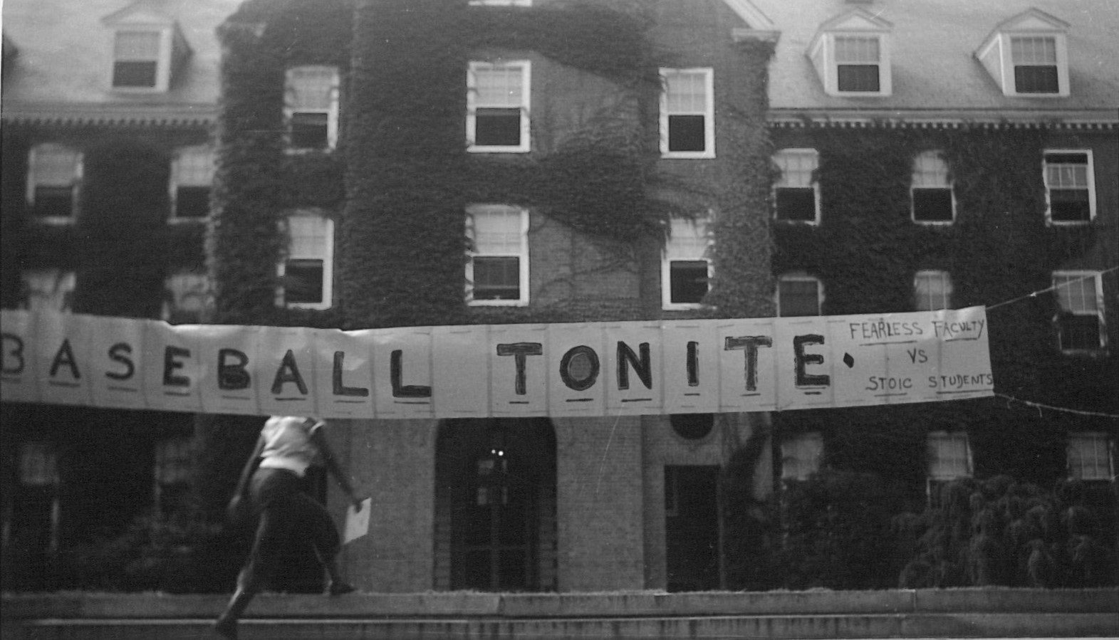 Black and white photo of a banner proclaiming "Baseball tonight" across a brick building.