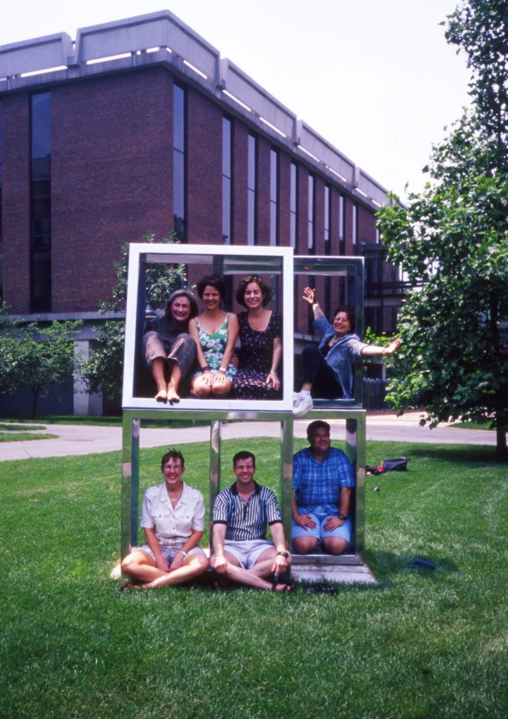 Color photo of seven individuals posing in a wooden frame.